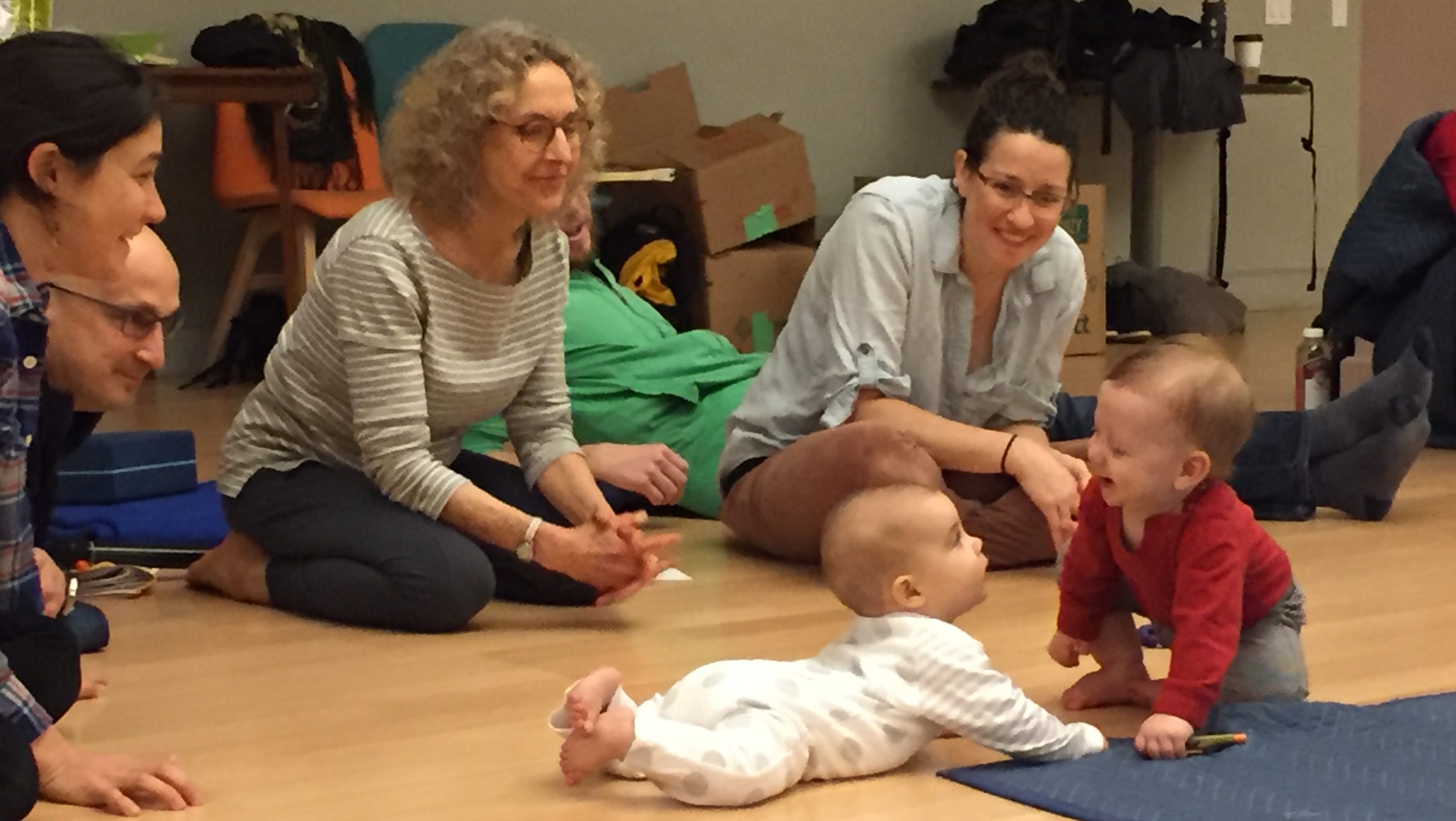 Ruella Frank sits on floor with babies and parents
